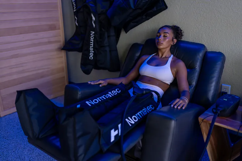Guest relaxing in a leather recliner wearing Normatec compression boots